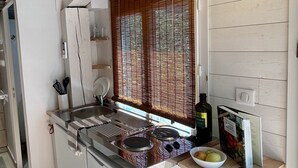 Una cucina compatta con fornello, lavello e un piccolo cestino.