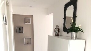 Un couloir avec une armoire blanche, un miroir et trois tableaux encadrés accrochés au mur.