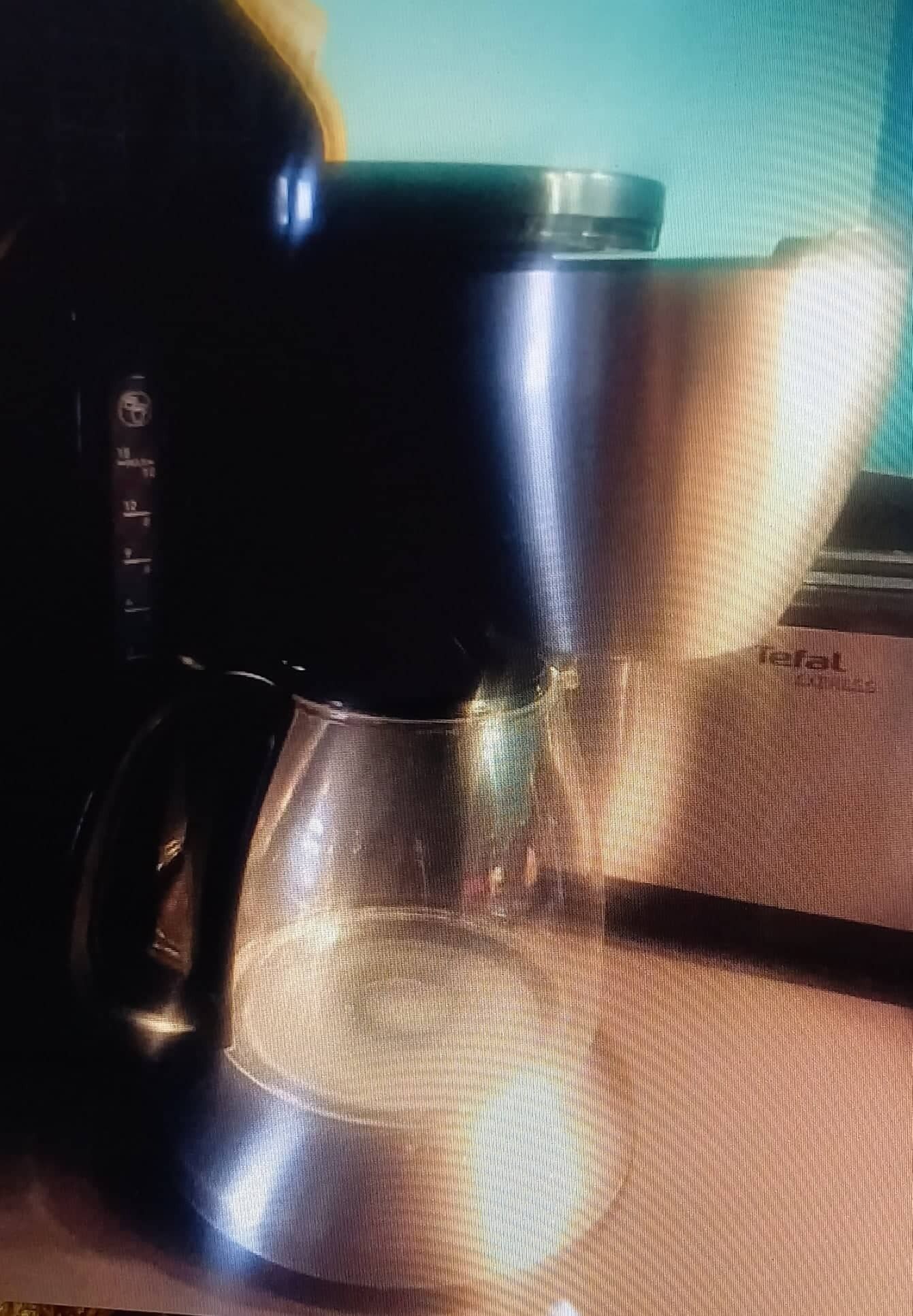 Una cafetera con jarra de vidrio transparente y tapa oscura, sobre una superficie con textura.