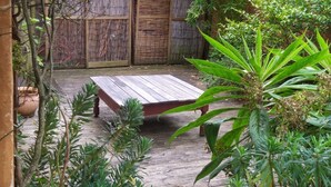 A wooden deck with a bench, surrounded by lush greenery and a bamboo fence. - Charming house between sea and countryside (Binic-Étables-sur-Mer)