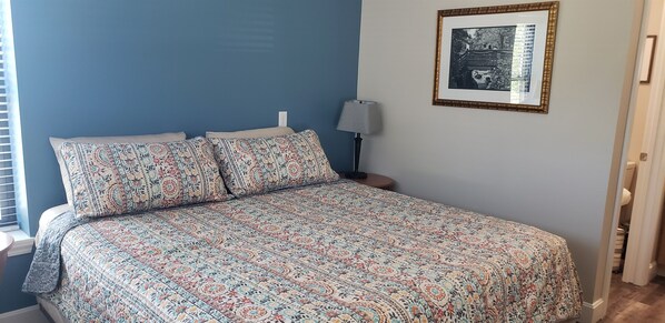 A bed with patterned bedding, a nightstand with a lamp, and a framed picture on the wall. - BOOK NOW-Huge Pool, Hot Tub, Arcade & more! (Branson)