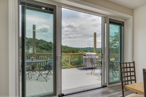 A deck with a table and chairs, a grill, and a view of a forested area. - BOOK NOW-Huge Pool, Hot Tub, Arcade & more! (Branson)
