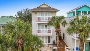A two-story building with a balcony on each floor, surrounded by palm trees. - Beaches and Dreams by Book That Condo (Panama City Beach)