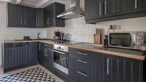 Una cocina moderna con armarios oscuros, un microondas, una cafetera y un horno empotrado.
