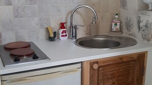 A compact kitchen with a built-in dishwasher, a sink, and a stove. - Cosy studio in a farmhouse  (UBRAYE)