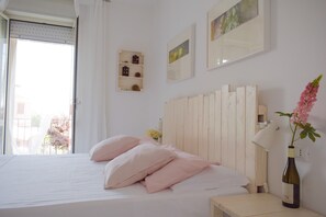 Un dormitorio con cama, mesita de noche, lámpara, botella y ventana con cortinas.