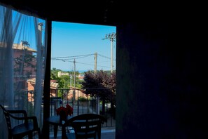 Un balcone con tavolo e sedie, affaccia su una zona residenziale con case e linee elettriche.