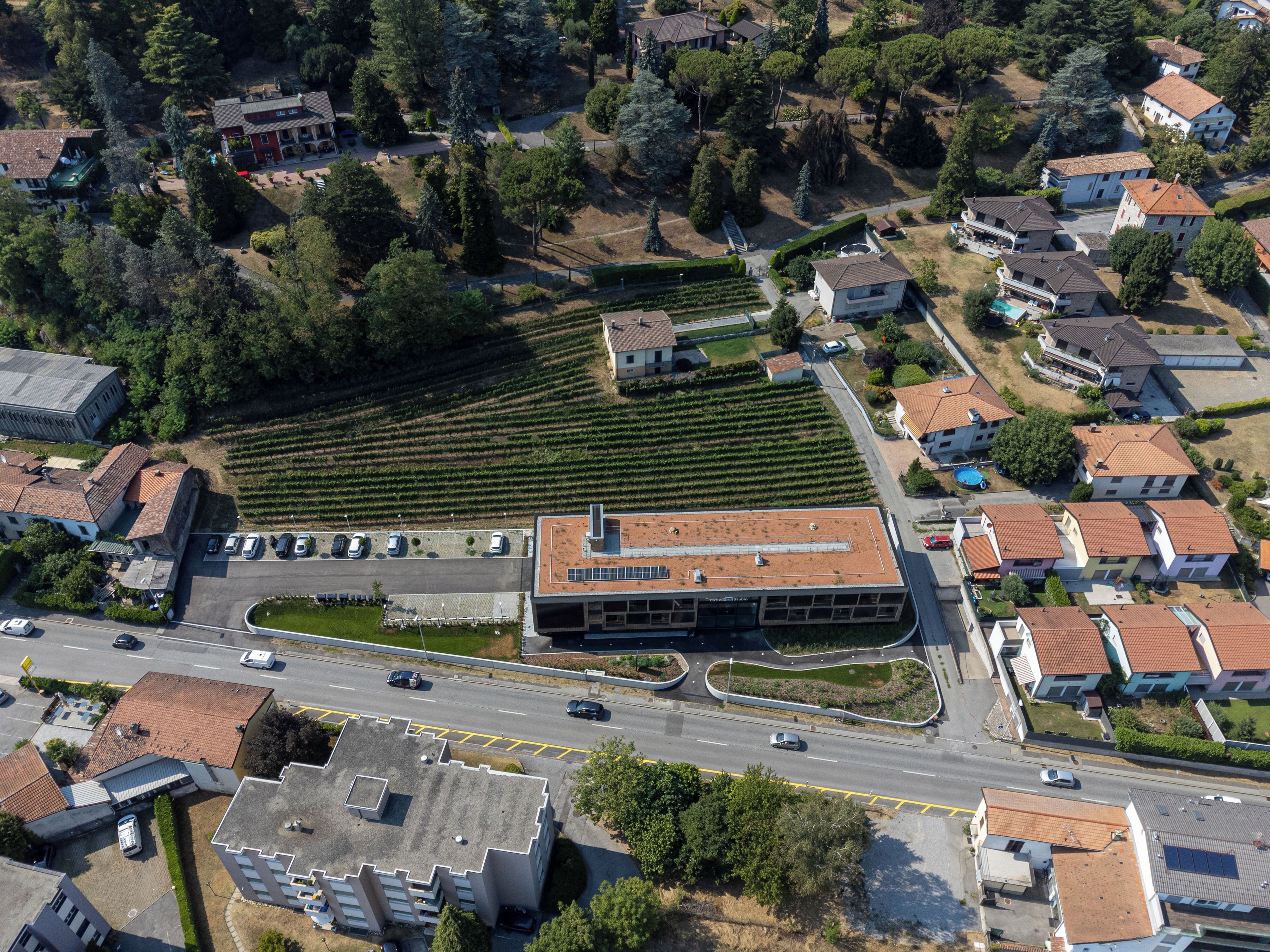 Vista aérea de un área residencial con un edificio grande de techo plano y un estacionamiento.