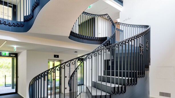 A spiral staircase with ornate black railings in a modern building. - Lo Scudo di Stabio (Stabio)