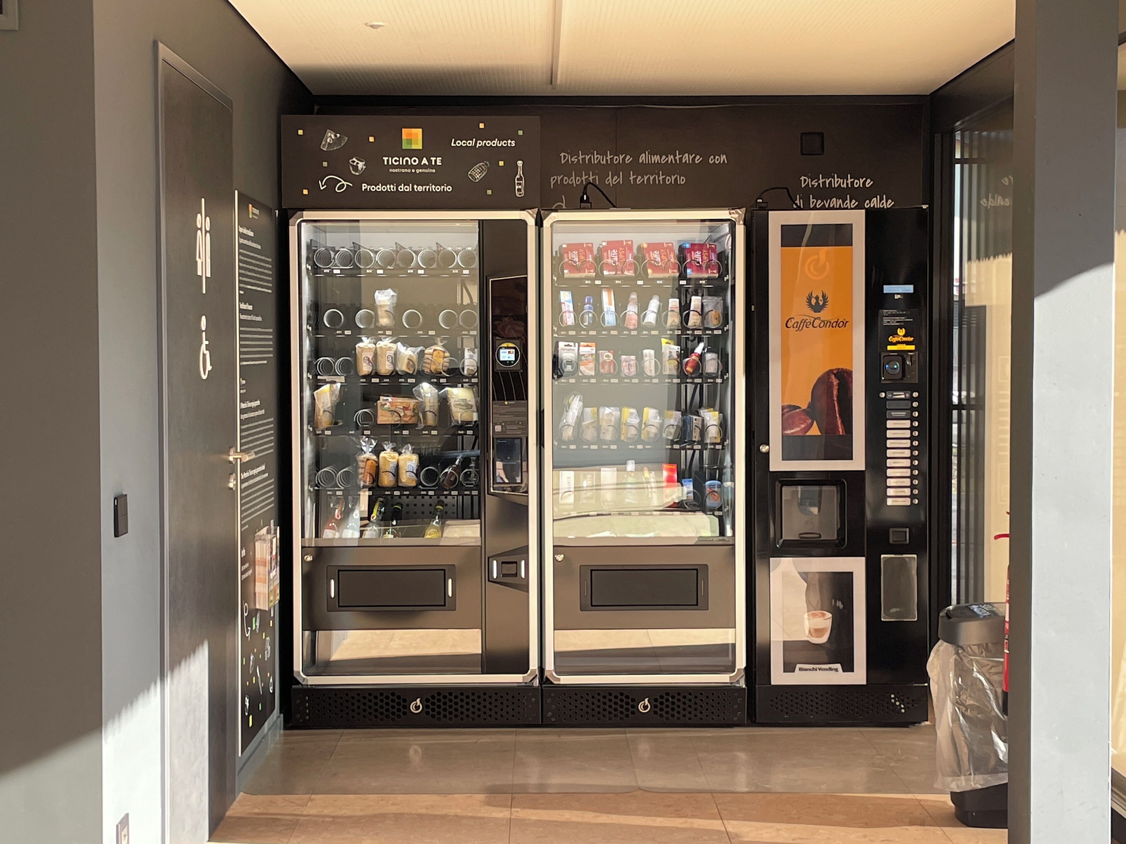 Un espace comprenant trois distributeurs automatiques, chacun étant rempli de différents produits alimentaires et boissons.