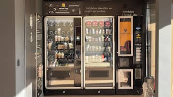 A vending machine area with three machines, each stocked with various food and drink items.