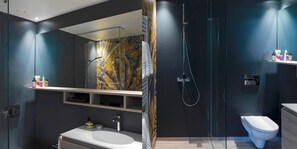 Enjoy a refreshing shower in the sleek bathroom with a large mirror, glass shower enclosure, and vibrant leaf-patterned wallpaper.