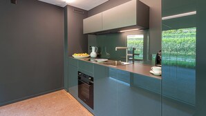 A modern kitchen with a built-in oven, a sink, and a window overlooking a garden. - Lo Scudo di Stabio (Stabio)