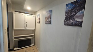 Un couloir avec une armoire blanche, une étagère et trois œuvres d’art encadrées accrochées au mur.
