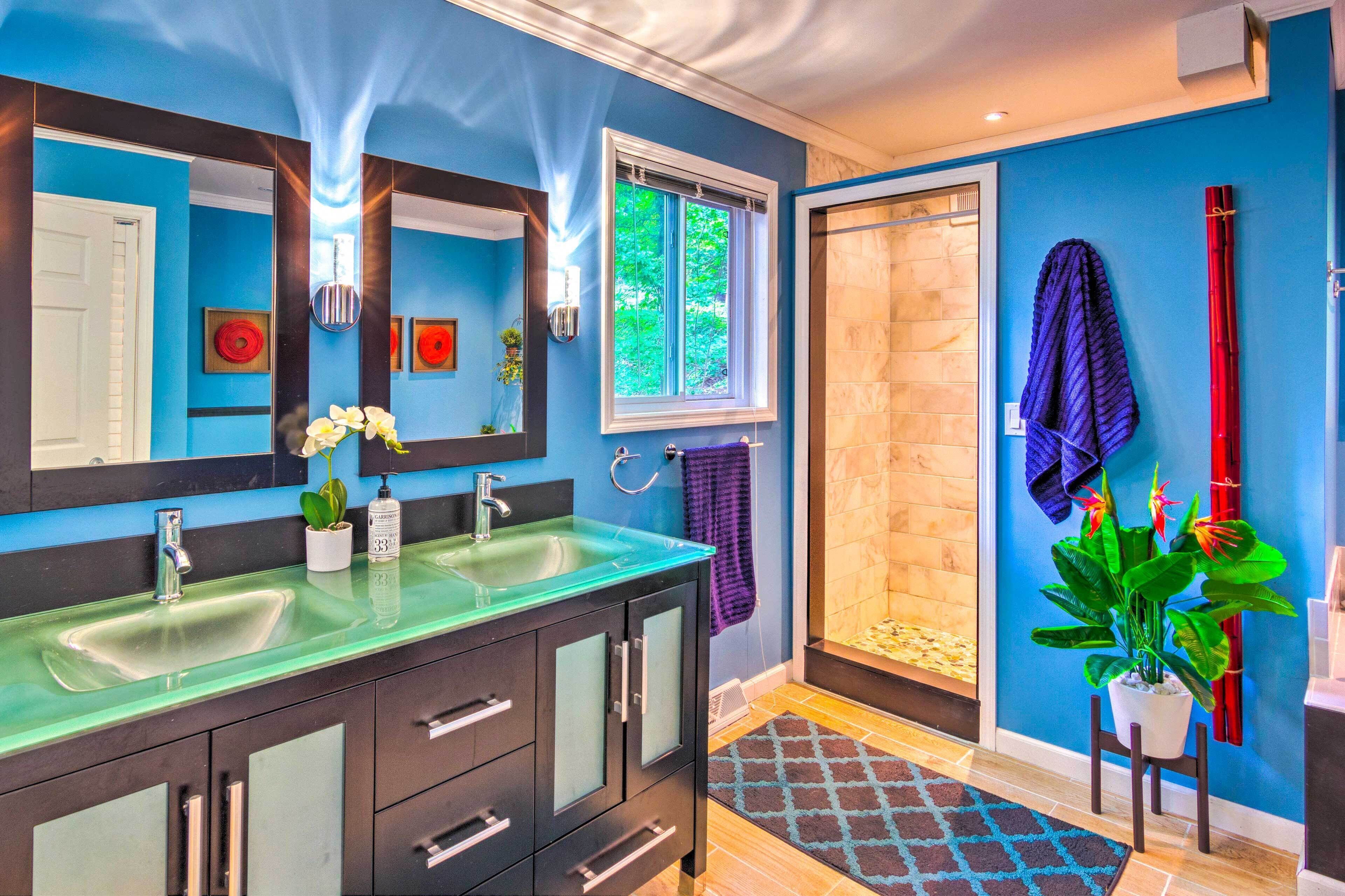 Une salle de bain moderne avec deux vasques, un grand miroir et un espace douche.