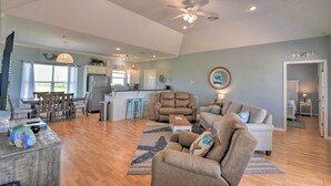 A spacious living area with a dining table, sofas, and a kitchen in the background. - Deck & Grill: Walkable Crystal Beach House! (Bolivar Peninsula)