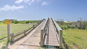 A wooden boardwalk with a caution sign, leading to a beach area. - Deck & Grill: Walkable Crystal Beach House! (Bolivar Peninsula)