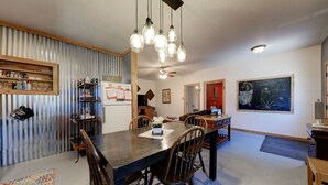 A dining area with a dark wooden table, chairs, and hanging light fixtures.