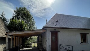 A house with a gravel driveway, a wooden pergola, and a thatched-roof structure. - The mountains win you over (Campan)