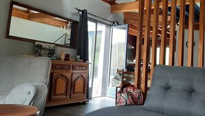 A spacious living room with a high ceiling, wooden beams, a chandelier, a grey sofa, a wooden cabinet, and a large mirror. - The mountains win you over (Campan)
