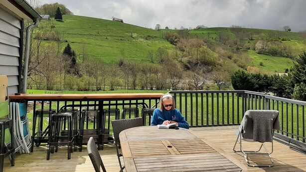 A deck with a table and chairs, overlooking a green hillside. - The mountains win you over (Campan)