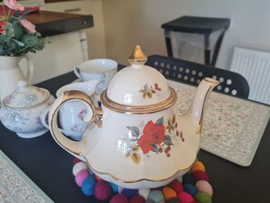 A white teapot with gold trim and floral designs, placed on a table with colorful pom-poms. - Lisheens Lodge (Kealkill)