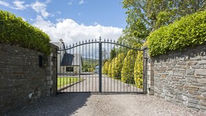 A gated entrance with a gravel path leading to a building. - Lisheens Lodge (Kealkill)