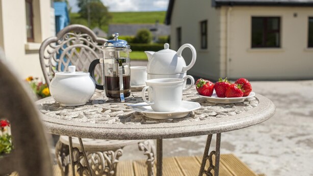 A round stone table with a white teapot, a French press, cups, and a plate of strawberries. - Lisheens Lodge (Kealkill)