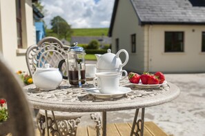 A round stone table with a white teapot, a French press, cups, and a plate of strawberries. - Lisheens Lodge (Kealkill)