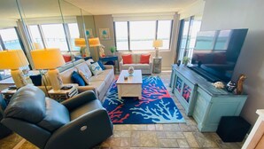 Een moderne woonkamer met een bank, fauteuil, salontafel en een televisie.