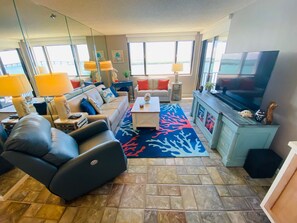 A modern living room with a sofa, armchair, coffee table, and a TV.