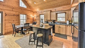L’intérieur d’une cabane en rondins, avec un îlot central, des armoires en bois et un réfrigérateur noir.