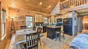 L’intérieur d’une cabane en rondins comprend un coin repas, une cuisine et une chambre à coucher située en mezzanine.