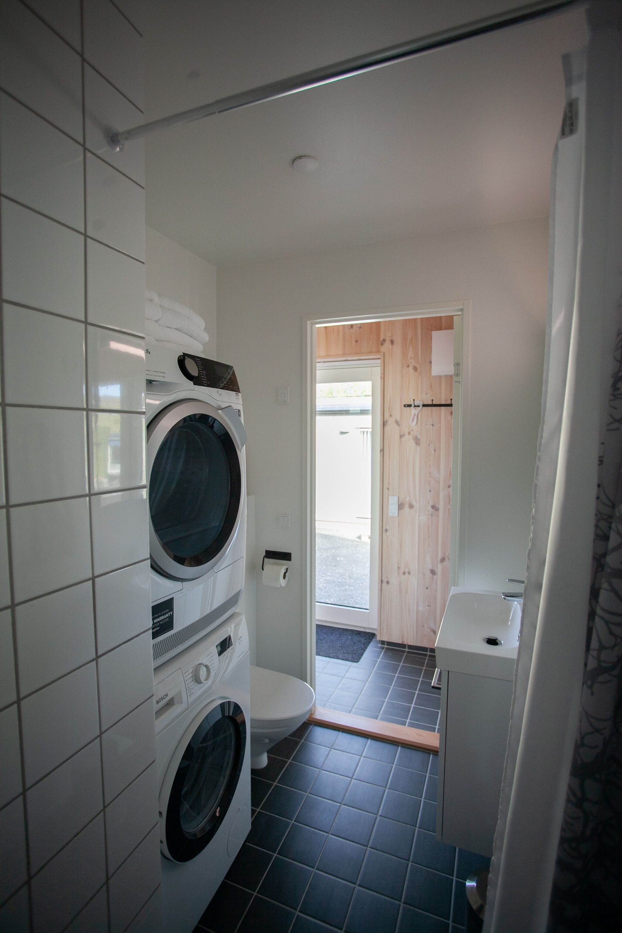 Ein kleines Badezimmer mit Waschmaschine, Toilette und einem kleinen Waschbecken.