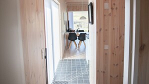 A hallway with wooden walls and a tiled floor leading to a dining area with chairs and a table. - Vacation Home - Scenic Nature - Sandoy (Sandur)