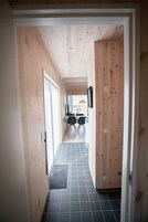 A hallway with wooden walls and a tiled floor leading to a dining area with chairs and a table.
