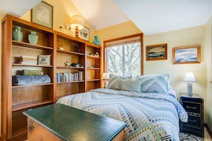 Un dormitorio acogedor con una cama grande, una estantería de madera y un escritorio.