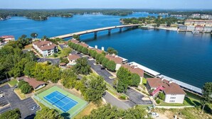 Luchtbeeld van een woongebied met een tennisbaan, een brug en een waterpartij.