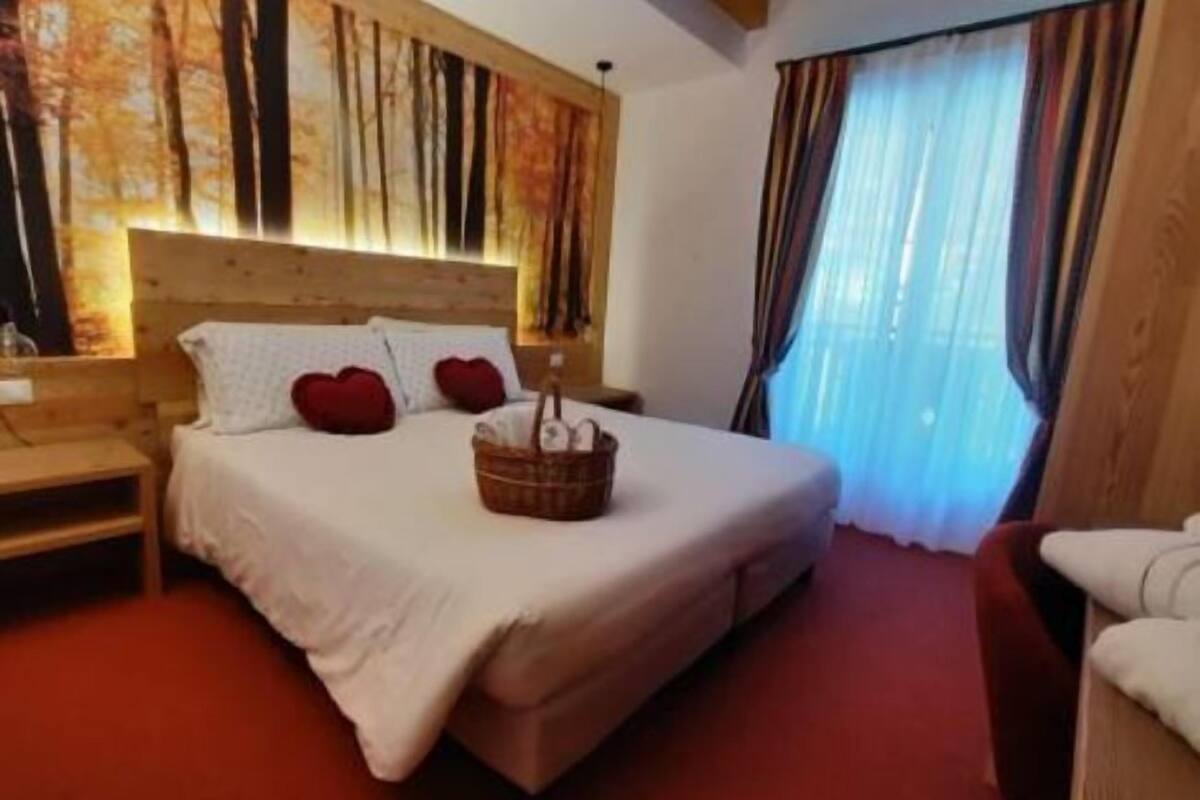 Ein Hotelzimmer mit einem großen Bett, einem Holz-Kopfteil, einem Nachttisch und einem Fenster mit Vorhängen.