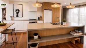 A modern kitchen with a central island, pendant lighting, and a view of the living area.