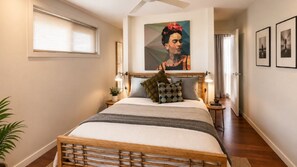 Ein Schlafzimmer mit einem Bett, Nachttischen, einem Gemälde und einem Fenster.
