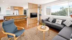 A modern living room with a grey sofa, a blue armchair, and a TV.