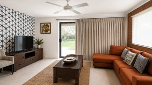 A living room with a TV, sofa, and a ceiling fan.