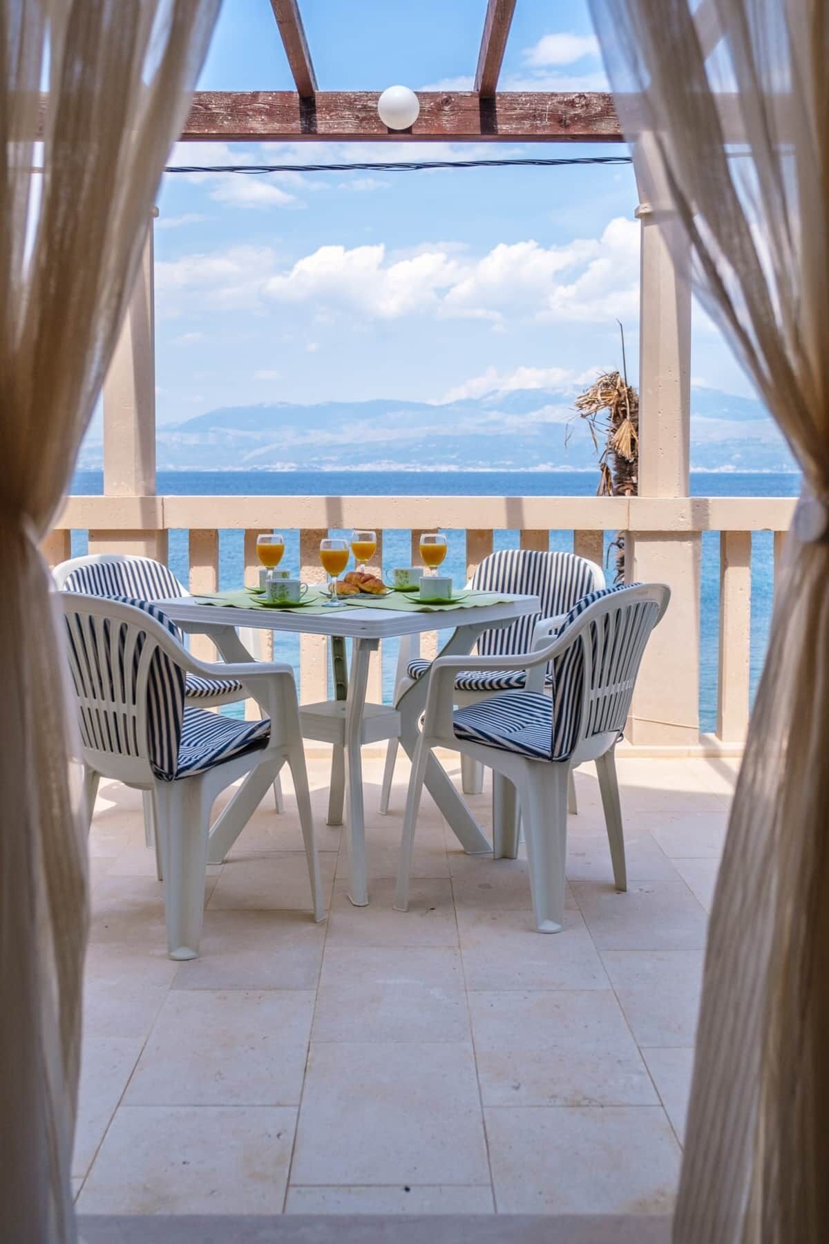 A terrace with a table set for two, overlooking a coastal view.