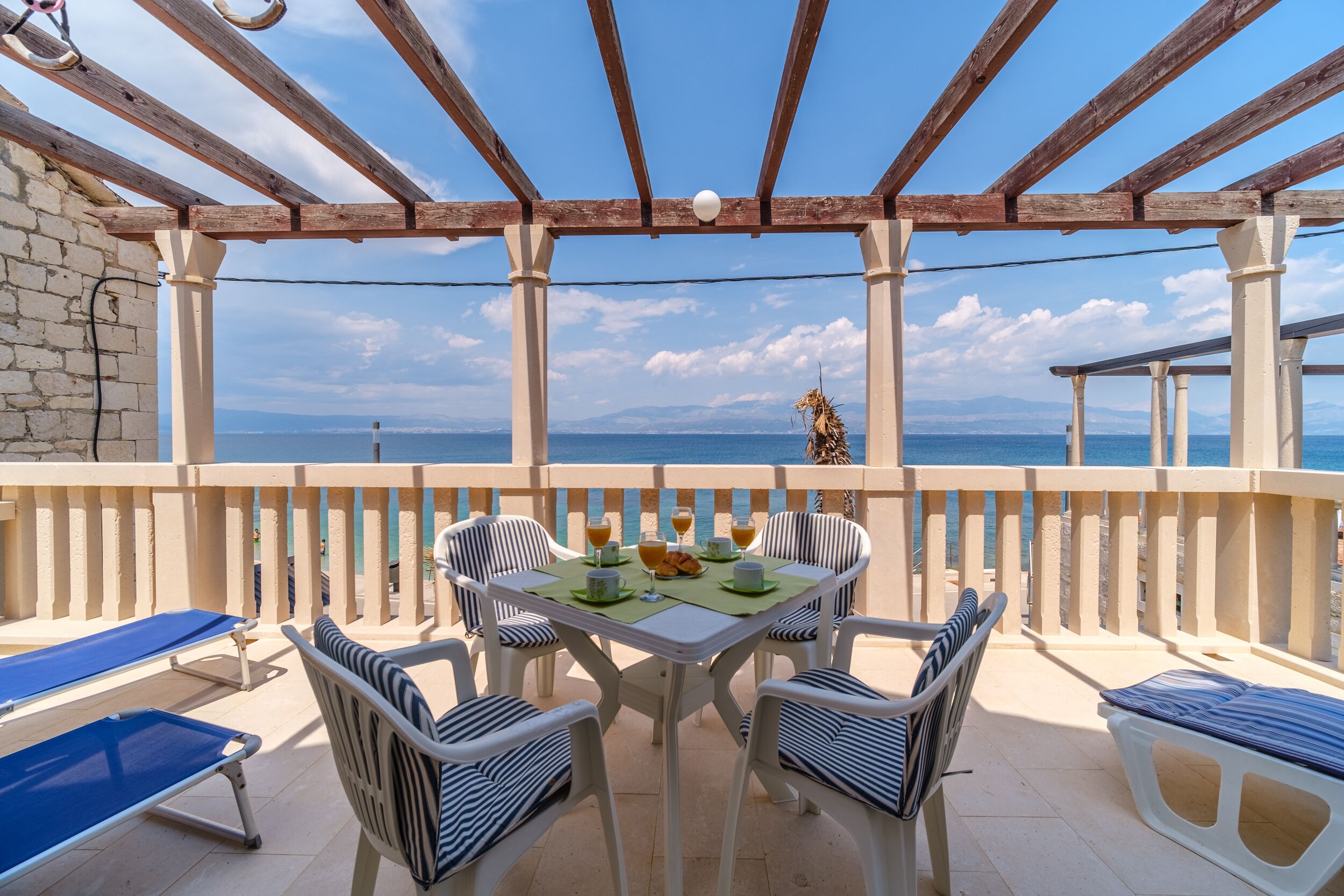 A terrace with a table set for breakfast, overlooking the sea.