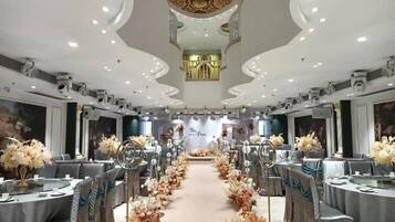 A banquet hall with round tables, floral centerpieces, and a central aisle.