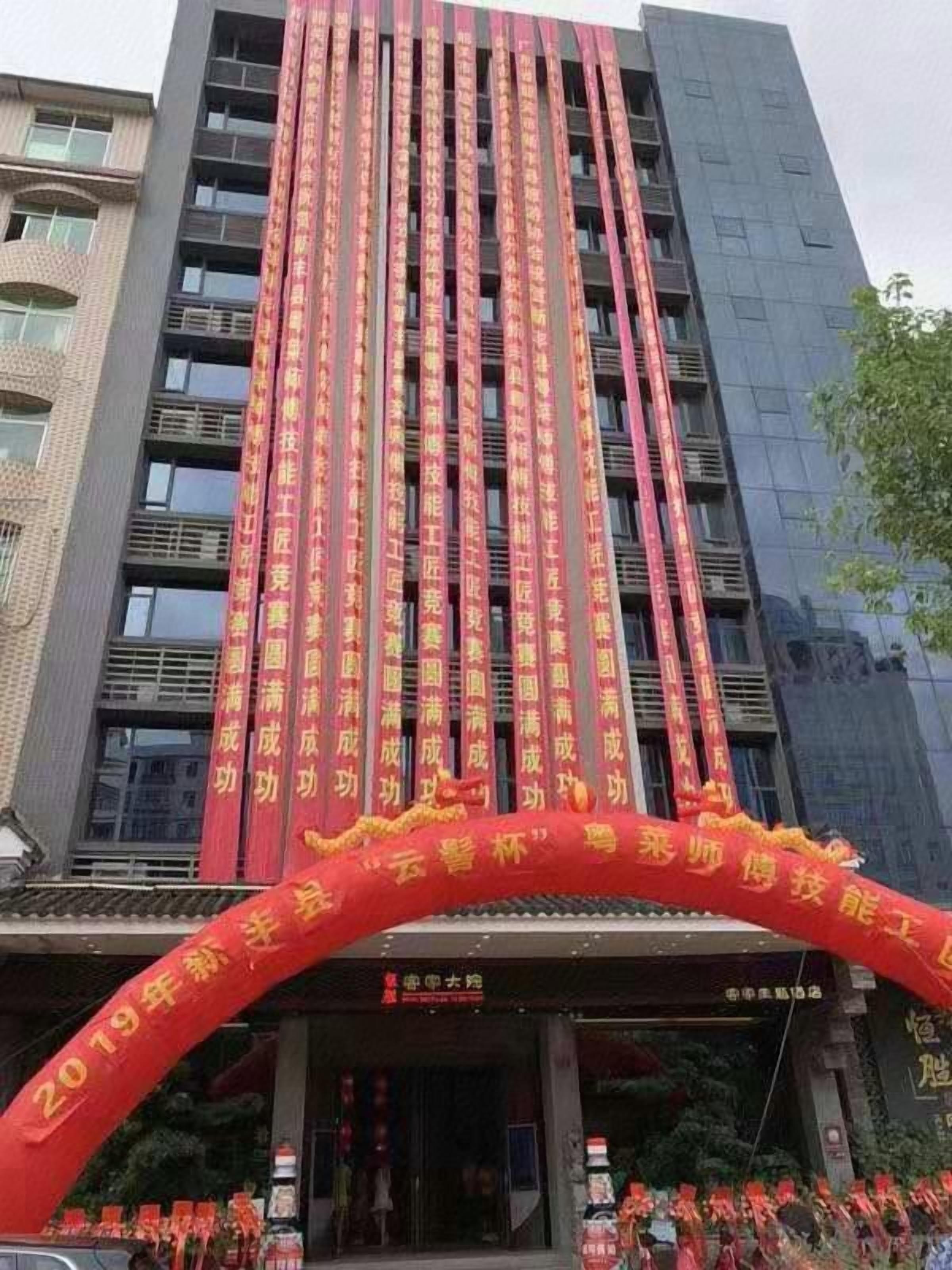 A building with vertical banners and a red archway with text.