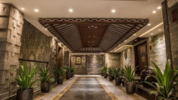 A corridor with a patterned ceiling, stone walls, and potted plants. - Hengsheng Kejia Courtyard (Xinfeng)