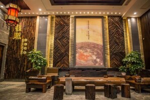 A lobby with a stage, seating area, and decorative elements. - Hengsheng Kejia Courtyard (Xinfeng)