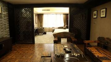 Ein Hotelzimmer mit Holzboden, einem Bett, einem Schreibtisch, einem Stuhl und einem Esstisch mit Spüle.